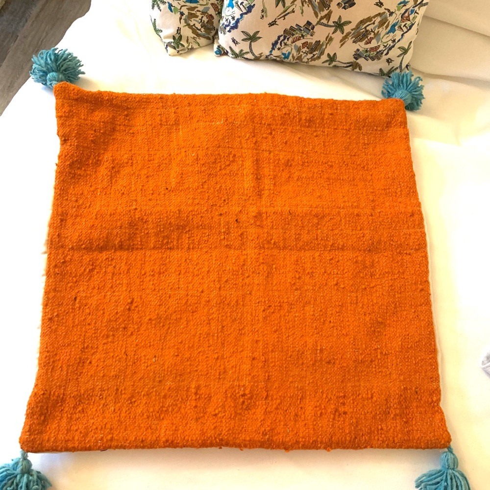 Orange pillow with turquoise tassels